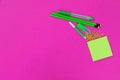 A group of bright green office requisites is lying in the upper right corner on pink background isolated