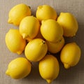 A group of bright yellow lemons is arranged on a textured beige cloth surface. The Royalty Free Stock Photo