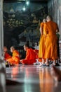 Group of Buddhist monks as tourists resting in the shadows on the territory of Grand Palace.