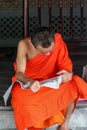 Group of Buddhist monks as tourists resting in the shadows on the territory of Grand Palace.