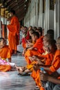 Group of Buddhist monks as tourists resting in the shadows on the territory of Grand Palace.