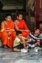 Group of Buddhist monks as tourists resting in the shadows on the territory of Grand Palace.