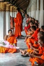Group of Buddhist monks as tourists resting in the shadows on the territory of Grand Palace.