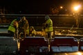 A group of builders repairs a bridge across the river at night under the light of lanterns in difficult winter conditions. Road Royalty Free Stock Photo