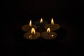 Group of burning small candles on a black background. Royalty Free Stock Photo