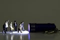 Group Of Business Figurines walking towards a stream of light from a miniature blue flashlight