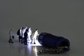 Group Of Business Figurines walking towards a stream of light from a miniature blue flashlight ht