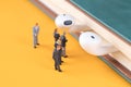 A group of business menÃ¢â¬â¢s miniature doll models are studying the headsets on the books Royalty Free Stock Photo