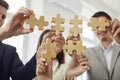 Group of business people assembling jigsaw puzzle at office. Cooperation, teamwork support concept. Royalty Free Stock Photo