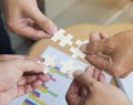 Group of business people assembling jigsaw puzzle wanting to put pieces of puzzle together on wood table backgroung for help suppo Royalty Free Stock Photo