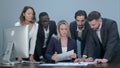 Group of business people busy discussing financial matter during meeting, standing around female boss desk