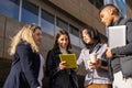 business people of different ethnicities dressed in smart casual having a work meeting with the tablet in the street Royalty Free Stock Photo