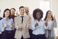 Group of business people looking at the camera, showing thumbs up sign and smiling. Royalty Free Stock Photo