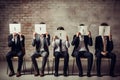 Group of business people sitting on chairs and covering their faces with letters, Young people hiding their faces behind paper