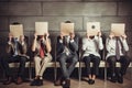 Group of business people sitting on chairs and covering their faces with paper, Young people hiding their faces behind paper