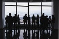 Group of business people standing in front of wide panaramic office windows. Silhouettes of different groups of businesspeople tal Royalty Free Stock Photo