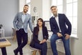 Group of business people of three looking at the camera and smiling at the workplace.