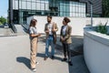 Group of business people walk outside in front of office buildings. Businessman and two businesswomen sharing experience ideas and Royalty Free Stock Photo