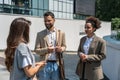 Group of business people walk outside in front of office buildings. Businessman and two businesswomen sharing experience ideas and Royalty Free Stock Photo