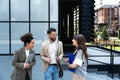 Group of business people walk outside in front of office buildings. Businessman and two businesswomen sharing experience ideas and Royalty Free Stock Photo