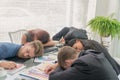 Group businessmen and women sleeping resting on workplace during work meeting, concept of exhausted businesspeople bored