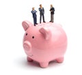 Group of businessmen share profits and savings. People in suits are standing on a piggy bank. Isolated on a white