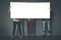 Group of businesspeople holding up a copyspace sign voicing their opinion at work with a grey background. People with Royalty Free Stock Photo