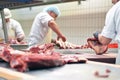 group of butchers works in a slaughterhouse and cuts freshly slaughtered meat (beef and pork) for sale and further processing as Royalty Free Stock Photo