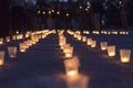 A group of candles burning in street and people holding candles in the background. Day of Memory of the Bereaved