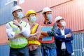 Group of cargo shipping container technician or engineer workers with hygiene mask stand fold arm and look same direction. Concept Royalty Free Stock Photo