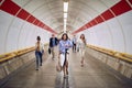 Group of caucasian people walking through pedestrian underground tunnel,  watching wrist watch, cell phone Royalty Free Stock Photo