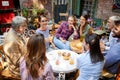 Group of caucasian young and senior people, male and female, sitting together in outdoor cafe talking, laughing, smiling Royalty Free Stock Photo