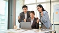 A group of cheerful Asian businesspeople are looking at a laptop screen, celebrating their good news Royalty Free Stock Photo