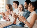 Group of cheerful businesspeople clapping while sitting in a row in a meeting together. Joyful business professionals Royalty Free Stock Photo