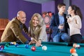 Group of cheerful charming positive friends playing billiards