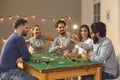 Group of cheerful friends betting, drinking and playing poker on table at home Royalty Free Stock Photo