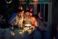 Group of cheerful friends blowing candles on the cake at the open air birthday party. Quality friendship time together