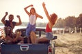 A group of cheerful friends is having fun in the back of a car by the sea. Summer, sea, vacation, friendship