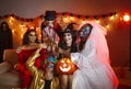 Group of cheerful friends in spooky halloween costumes posing with glasses of champagne in hands. Royalty Free Stock Photo