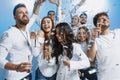 Group of cheerful joyful young people standing and celebrating together over blue background Royalty Free Stock Photo