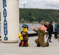 Group of cheerful mascots dressed in military uniforms on the street with people in the background