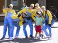 A group of cheerful men in Minions costume dressed take pictures with children