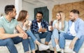 Group of cheerful multiethnic friends having party at home, sitting on couch, drinking coffee Royalty Free Stock Photo