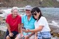 Group of cheerful senior Caucasian friends in leisure travel at sea sitting looking together at mobile phone. Three seniors Royalty Free Stock Photo