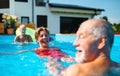 Group of cheerful seniors in swimming pool outdoors in backyard, having fun. Royalty Free Stock Photo