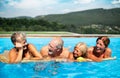 Group of cheerful seniors in swimming pool outdoors in backyard, relaxing and talking. Royalty Free Stock Photo