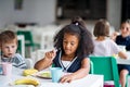 A group of cheerful small school kids in canteen, eating lunch. Royalty Free Stock Photo