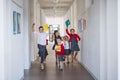 A group of cheerful small school kids in corridor, running and jumping. Royalty Free Stock Photo