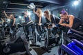 Group of cheerful sporty girls training on fitness bikes and having fun together on cycling class in gym Royalty Free Stock Photo