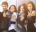 Group of cheerful students point their finger up